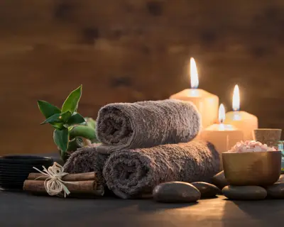 Brown towels with bamboo and candles for relax spa massage and body treatment. Beautiful composition with candles, spa stones and salt on wooden background. Spa and wellness setting ready for beauty treatment.