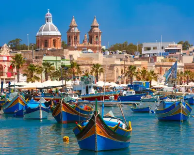 Traditional eyed colorful boats Luzzu in the Harbor of Mediterranean fishing village Marsaxlokk, Malta