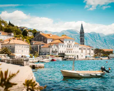 Classic panorama view of the historic town of Perast located at world-famous Bay of Kotor on a beautiful sunny day with blue sky and clouds in summer, Montenegro, southern Europe.
